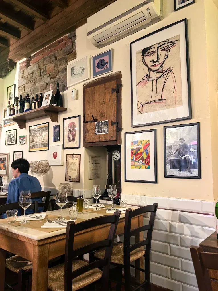 La saletta di Vini e Vecchi Sapori con le pareti coperte di quadri e ritratti regalati dai clienti