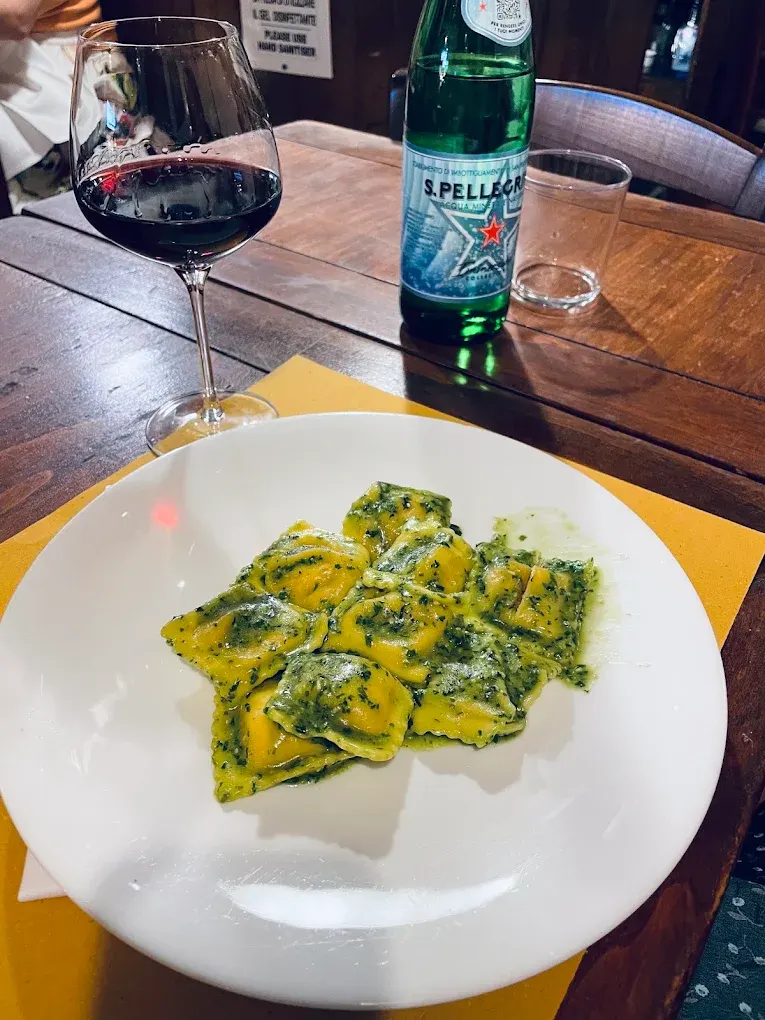 Ravioli verdi con bicchiere di vino rosso sulla tovaglietta gialla