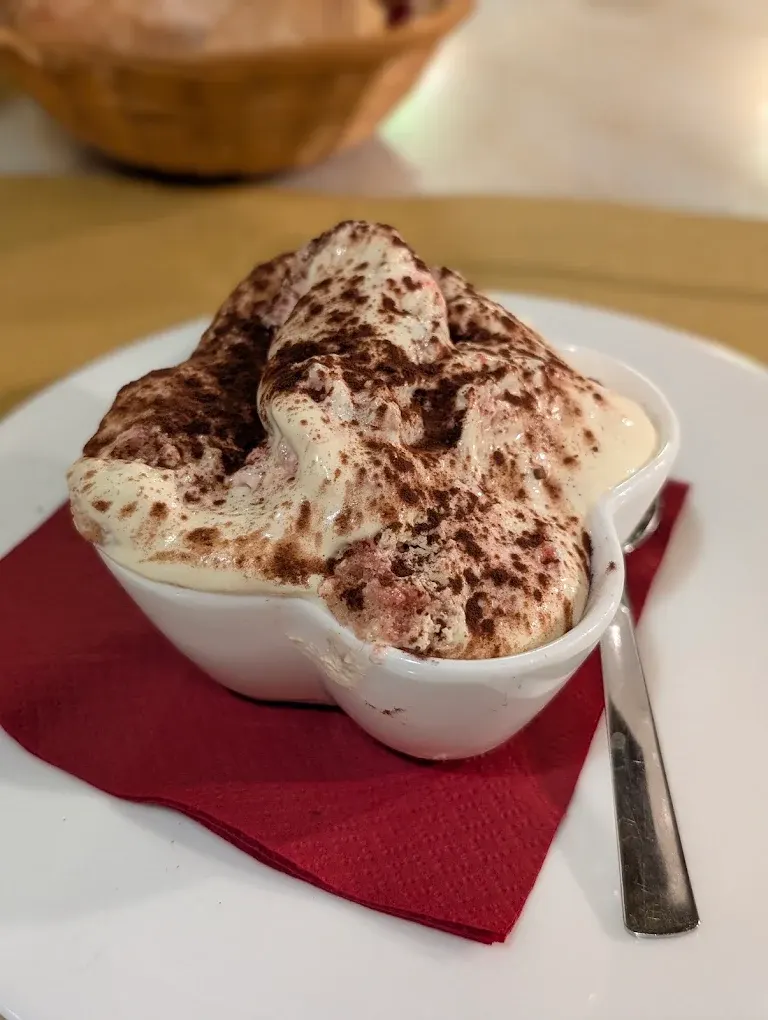 Tiramisù ai lamponi nella coccetta bianca sul tovagliolo rosso